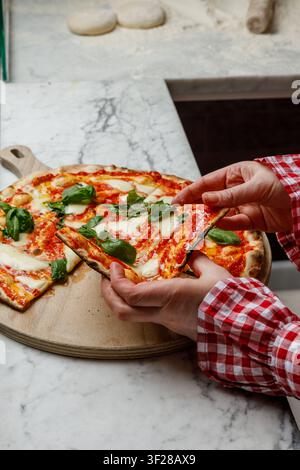 Une jeune femme prend une part de pizza fraîchement cuite. Banque D'Images