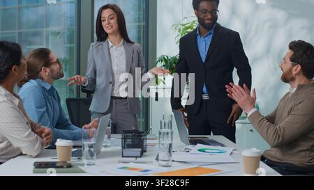 Femme de patron caucasien invitant homme afro-américain présentant le nouveau travailleur à l'équipe d'affaires multiethnique à la réunion de bureau. Recruteur de femme d'affaires Banque D'Images