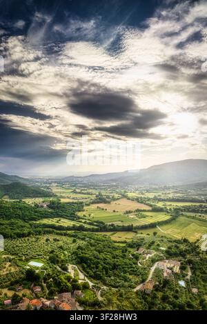 Vue aérienne des collines ondulantes et de la campagne entourant Castiglion Fiorentino, avec des champs verdoyants, des oliveraies et des nuages dramatiques. Ca Banque D'Images
