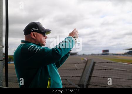 Un fan filme avec son iPhone à Silverstone pendant le Grand Prix de Grande-Bretagne, avec le circuit visible en arrière-plan Banque D'Images