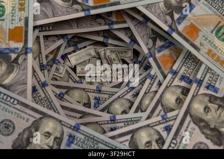 Petits piles de billets à l'intérieur d'un tunnel tourbillonnant de billets de cent dollars américains Banque D'Images