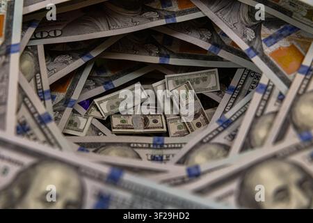 Petits piles de billets à l'intérieur d'un tunnel tourbillonnant de billets de cent dollars américains Banque D'Images