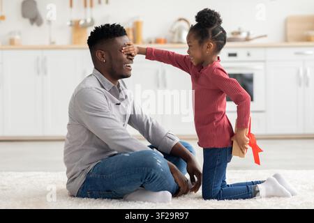 Père et fille noirs heureux jouant ensemble à la maison, s'adonnant à une activité amusante Banque D'Images