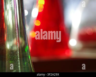 Grossissement d'objets en verre avec arrière-plan flou. Au premier plan, une surface en verre vert transparent avec une texture visible, reflétant la lumière. Backg Banque D'Images
