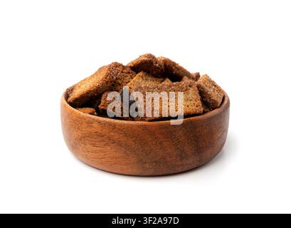 Croutons de seigle dans un bol en bois isolé, pain complet grillé fait maison, cubes de pain croustillants éparpillés, miettes de crouton de seigle sec, crackers rôtis au sel brun Banque D'Images