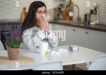 Jeune femme souffrant de rhume ou d'allergie soufflant le nez Banque D'Images