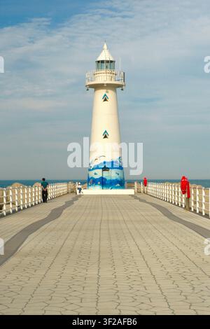 Busan, Corée du Sud – 30 mai 2026 : Le phare blanc de Cheongsapo au bout d'une jetée, avec des visiteurs marchant le long de la promenade. Banque D'Images