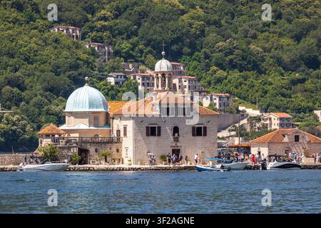 Perast, Monténégro - 13 juin 2023 : Église de pèlerinage et musée sur une île artificielle attirant touristes et bateaux Banque D'Images