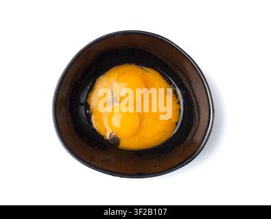 Jaunes d'œufs battus dans un bol, œufs de poule frais pour recette de cuisine, jaunes d'œufs biologiques mélangés dans un bol noir Banque D'Images