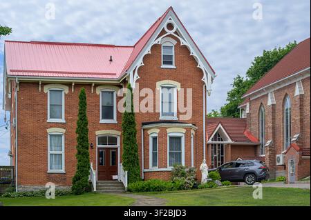 Bâtiment en briques avec toit rouge à côté d'une église en briques. Banque D'Images