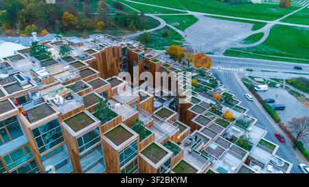 Vue aérienne d'un complexe d'appartements moderne en bois avec des toits-terrasses verdoyants et des balcons entourés de parcs et d'arbres d'automne, Suède. Banque D'Images