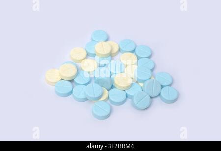 Comprimés de médicament bleus et jaunes disposés en pile sur un fond clair, adaptés à la santé, à la pharmacie, aux médicaments, aux compléments alimentaires, au traitement Banque D'Images