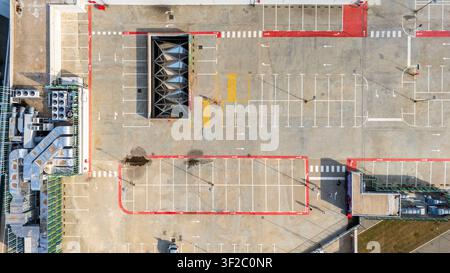 Vue aérienne d'un parking sur toit avec des places de stationnement marquées, des marquages routiers rouges et des unités de ventilation industrielles à Novi Sad, Vojvodina, Serbie. Banque D'Images