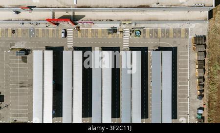 Vue aérienne d'un parking moderne avec des rangées de structures de stationnement couvertes et des places marquées adjacentes à un grand bâtiment commercial à Novi Sad, Voj Banque D'Images