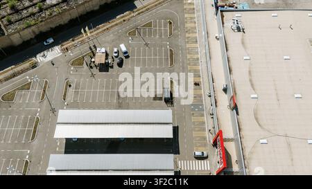 Vue aérienne d'un parking avec des structures de stationnement couvertes et un grand bâtiment de vente au détail à Novi Sad, Vojvodina, Serbie. Banque D'Images