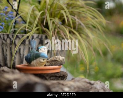 Scène de jardin à mise au point sélective mettant en vedette une figurine bleue décorative à côté de graminées ornementales Banque D'Images