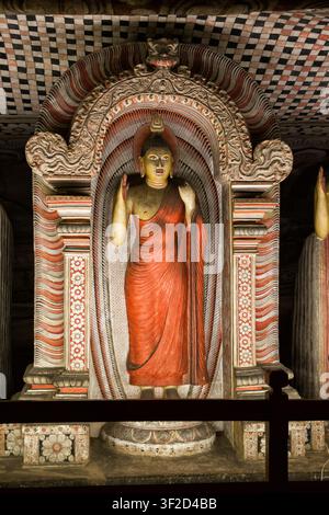 Statue de Bouddha debout ornée d'une robe rouge dans le temple des grottes de Dambulla Banque D'Images