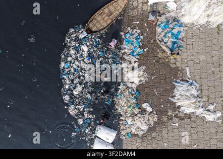 Dhaka, Bangladesh - 23 janvier 2026 : Vue aérienne de personnes collectant des déchets plastiques dans les eaux polluées de la rivière Buriganga près d'un bateau en bois Banque D'Images