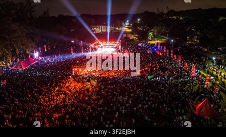 Vue aérienne d'un grand concert de musique en plein air de nuit avec des lumières de scène vives illuminant une foule massive au Ghana. Banque D'Images