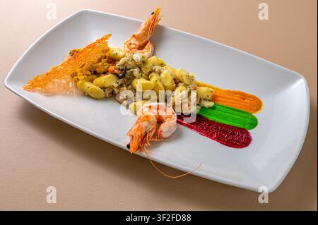 Gnocchi alla marinara aux crevettes et fruits de mer, élégamment dressés avec des sauces de légumes colorées dans une présentation de fine dining contemporaine. Banque D'Images