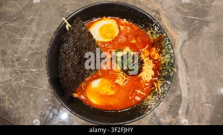 Bol de nouilles ramen épicées servi dans un bouillon savoureux avec des ingrédients et des garnitures asiatiques traditionnels. Banque D'Images