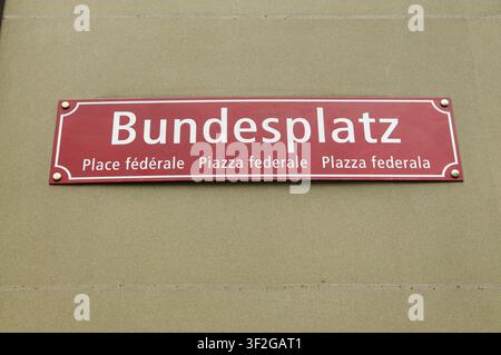 Vue rapprochée du panneau de rue rouge officiel de Bundesplatz (Place fédérale) monté sur un mur en grès. Le panneau affiche le nom en allemand, Frenc Banque D'Images
