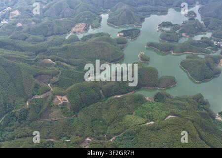 Capturée à plus de 1 100 mètres d'altitude, cette vue aérienne d'un réservoir de montagne dans le sud de la province de Fujian révèle une tapisserie époustouflante de vert de jade Banque D'Images