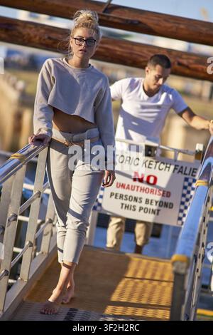 Couple prenant des pas interdits, femme confiante dans sa relation, personne marchant pieds nus sur un quai, avec un panneau "Accès interdit aux non-autorisés" à l'arrière-plan Banque D'Images