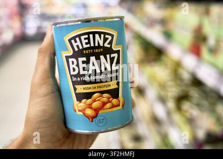 Une boîte de Heinz Beanz en sauce tomate est tenue dans la main, clairement étiquetée, contient beaucoup de protéines, langue anglaise, haricots, haricots blancs, Penny Disco Banque D'Images