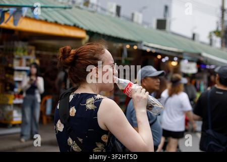 BANGKOK, THAÏLANDE - 12 JUILLET 2026 : Femme buvant un soda, profil latéral. Banque D'Images
