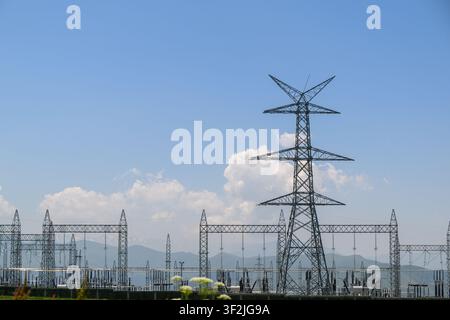 Hauteurs tours d'alimentation électrique en acier sous un ciel bleu clair. Équipement de sous-station électrique visible en arrière-plan Banque D'Images