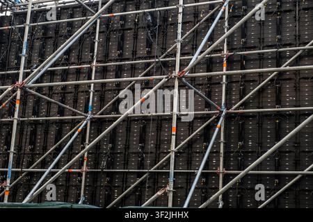 une structure d'échafaudage temporaire construite pour soutenir un grand mur vidéo LED extérieur, souvent utilisé pour des concerts ou des événements Banque D'Images