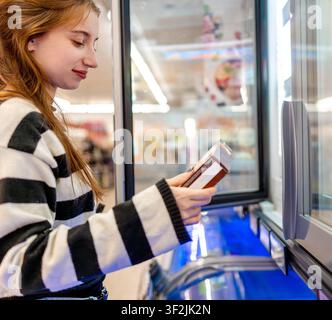 Femme choisissant la crème glacée dans le supermarché Banque D'Images