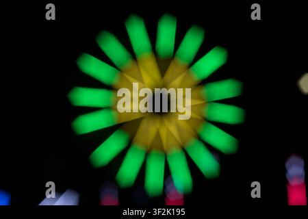 Grande roue vibrante dominant un fond sombre, générant une atmosphère excitante et joyeuse pendant un événement nocturne. La structure illuminée crée une ambiance festive Banque D'Images
