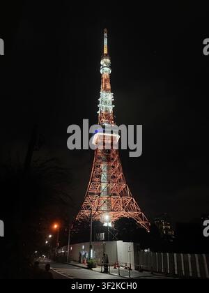 12 août 2025, Minato, Tokyo, Japon – La Tour de Tokyo illuminée en orange la nuit, prise d’un angle oblique bas dramatique montrant la structure en treillis d’acier contre un ciel sombre. Banque D'Images