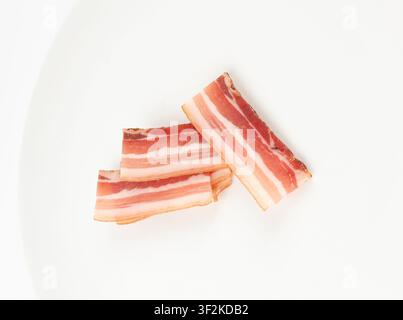 Porc carbonara séché isolé, tranches de bacon fumé cru, tranches de brisket rayées, bacon fin et frais tranché sur fond blanc, vue par-dessus Banque D'Images