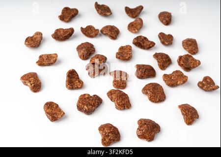 Flocons de céréales au chocolat isolés, petit-déjeuner de riz croustillant. Tas de maïs et de céréales au chocolat, céréales au caramel en gros plan sur fond blanc à Banque D'Images