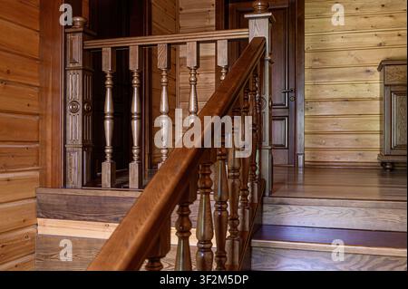 Intérieur en bois chaleureux comprenant un escalier avec une rampe sculptée. Les murs sont lambrissés, ajoutant à l'ambiance rustique Banque D'Images