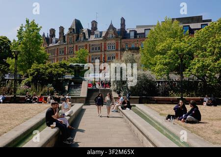 Des personnes et des couples se détendent près des canaux d'eau dans les Peace Gardens en regardant vers la grande architecture en brique de Pinstone Street à Sheffield, Royaume-Uni. Banque D'Images
