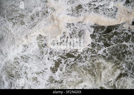 Vue aérienne d'écume de mer agitée et de vagues blanches s'écrasant sur les rochers des falaises de Bempton, dans l'East Yorkshire Banque D'Images