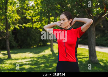 Femme s'étire en plein air dans un parc par une journée ensoleillée Banque D'Images