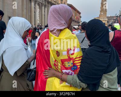 Trois femmes portant des hijabs participent à la retransmission publique de la finale de la Coupe du Monde de la FIFA 2026 entre l'Espagne et l'Argentine sur la Plaza del Pilar, à Saragosse Banque D'Images