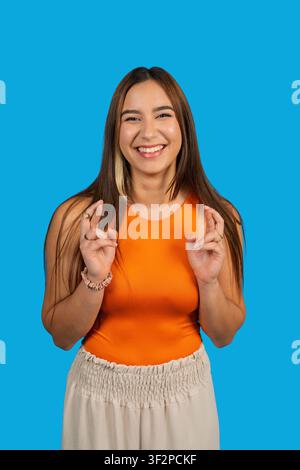 Jeune femme souriant et croisant les doigts représentant l'espoir et la bonne fortune Banque D'Images