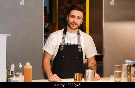 Barista Se Tenant Au Comptoir Se Tenant À La Caméra De La Boutique De Café Banque D'Images