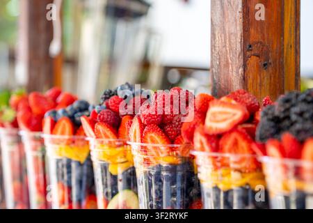 Pièces de fruits frais variés dans des gobelets en plastique transparent disposés sur les étagères du magasin. Les gobelets de salade de fruits sains sont prêts à être vendus. Aliments Banque D'Images