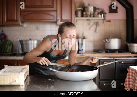 Femme sentant une nourriture délicieuse pendant qu'elle cuisine Banque D'Images
