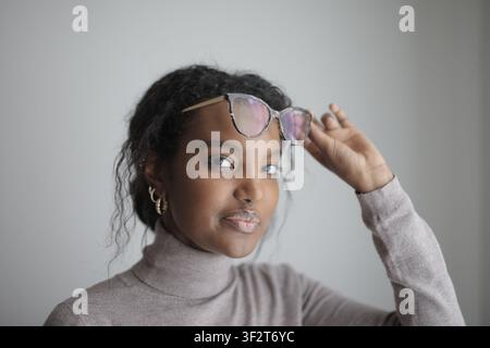 Jeune femme noire soulève ses lunettes sur son front Banque D'Images