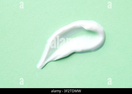 Tache de crème de soins blanche sur fond de menthe pour la texture d'un produit de beauté et l'échantillon de crème hydratante Banque D'Images