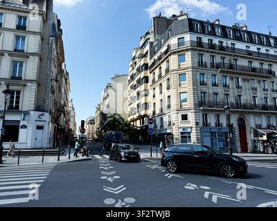 Paris, France - 14 mai 2026 : Vue large d'une intersection de rue parisienne mettant en scène l'architecture Haussmann, la circulation, les cyclistes et les piétons dans la lumière du jour. Banque D'Images