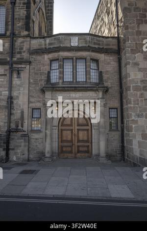Vue de l'entrée historique de la bibliothèque de l'Université de Durham présentant une maçonnerie en pierre, des portes en bois cintrées et des fenêtres en verre plombé à Durham, Engla Banque D'Images